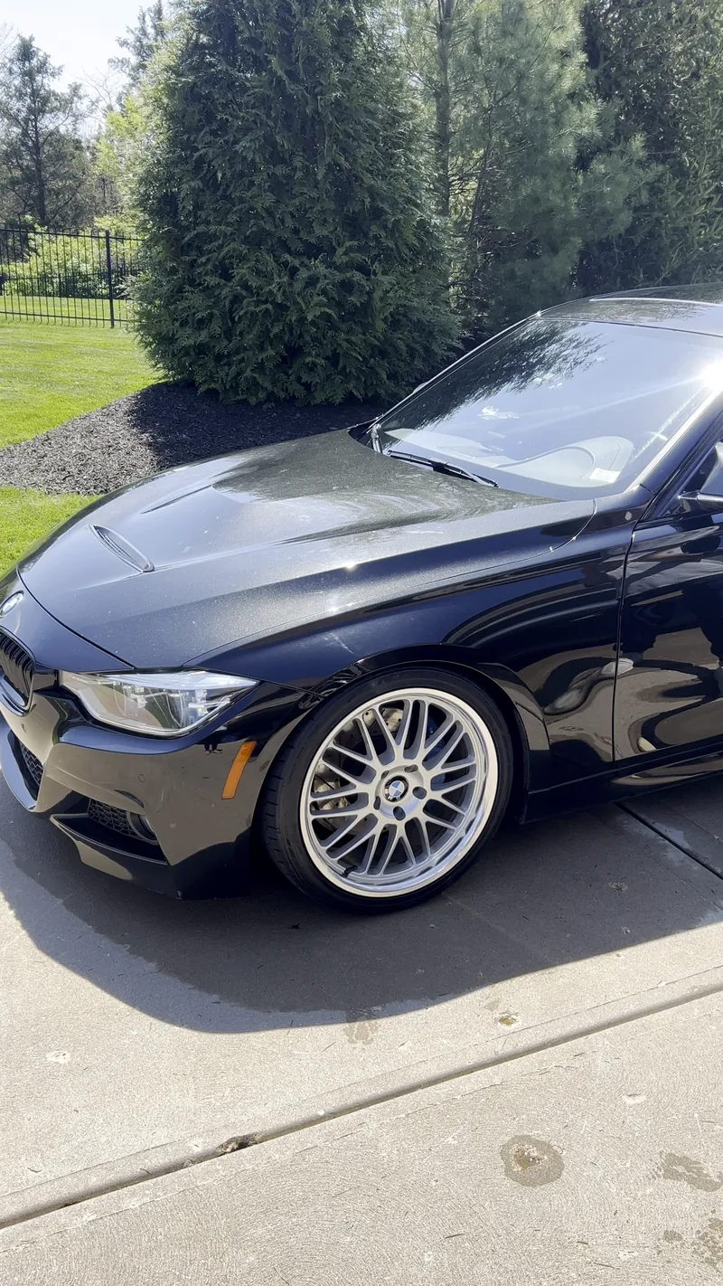 Black BMW 3 Series in bright sun after an exterior detail, with a glossy hood and polished wheel